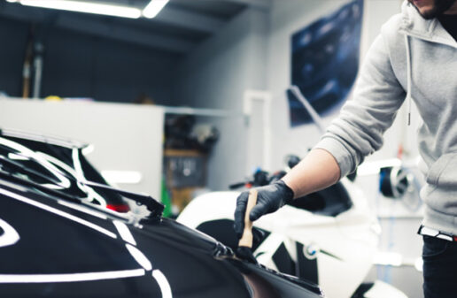 Car expert cleaning the dust of sports car with a car detailing brush