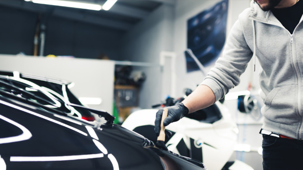 Car expert cleaning the dust of sports car with a car detailing brush