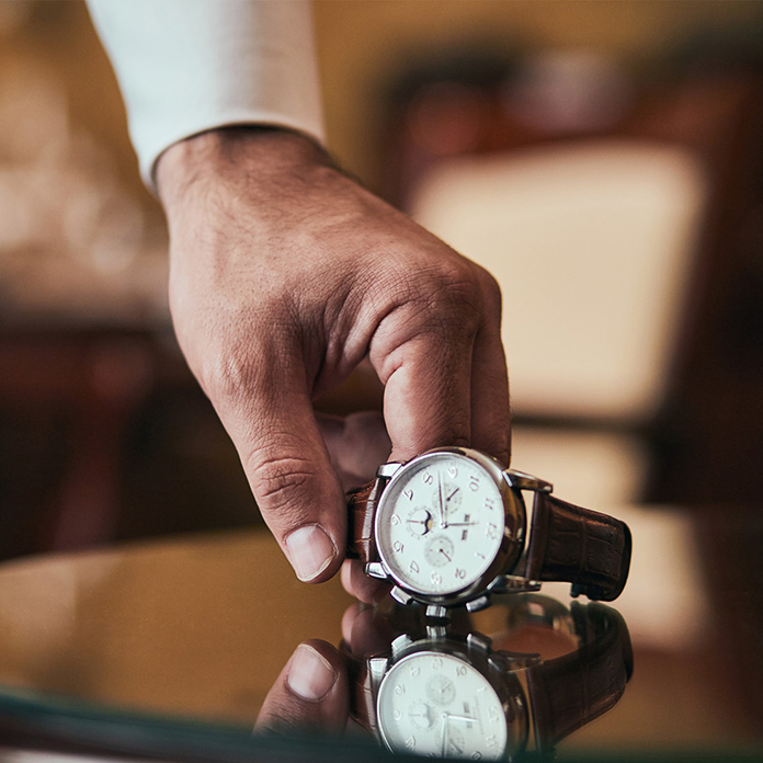 Mans hand holding watch on table